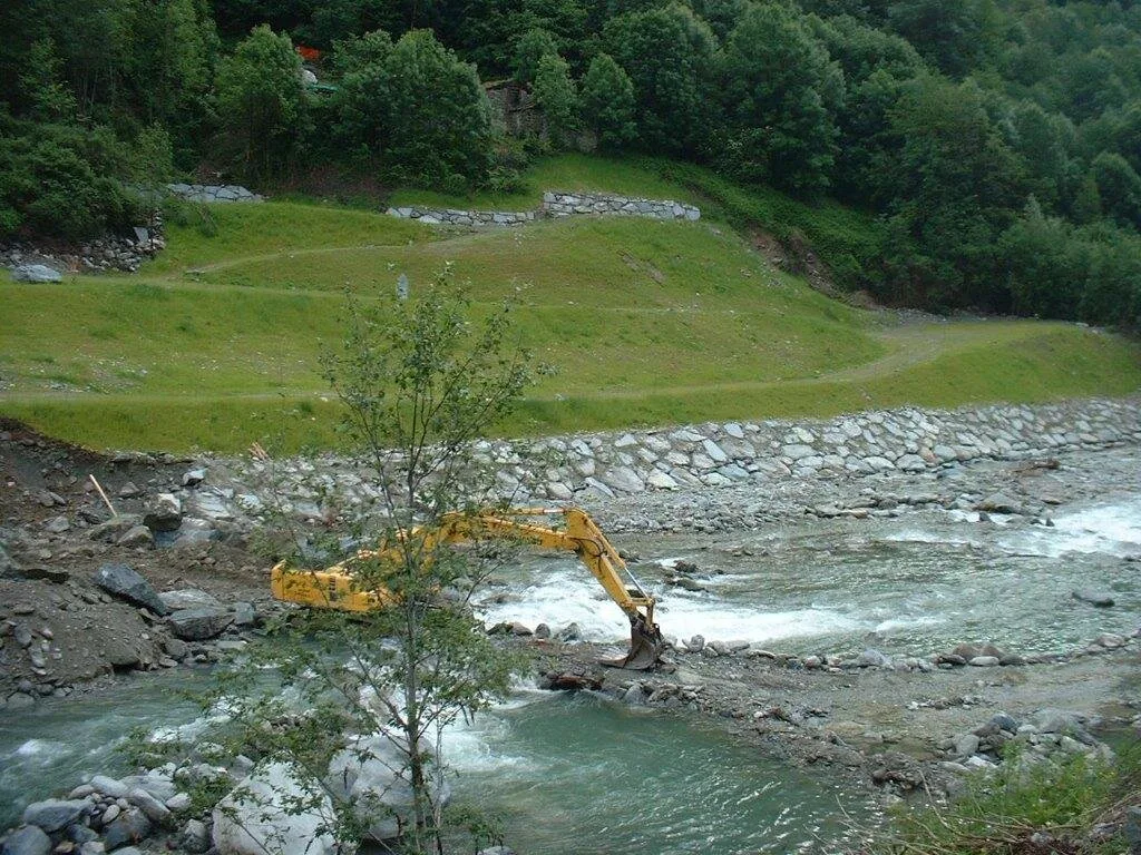 Escavatore al lavoro in alveo e sponda in pietrame